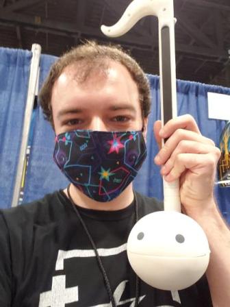 Musical_daredevil, masked, facing the camera, holding an otamatone